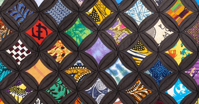 Viola Canady’s colorful quilt, with bright patterned fabric set in a black, cathedral-window grid.